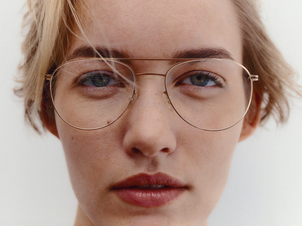 A close up of a person wearing aviator metal-framed glasses that suit their face.
