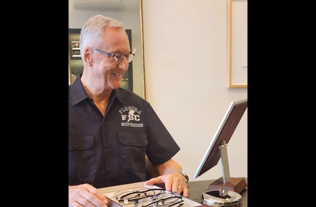 Adult trying on different glasses frames at an optician office